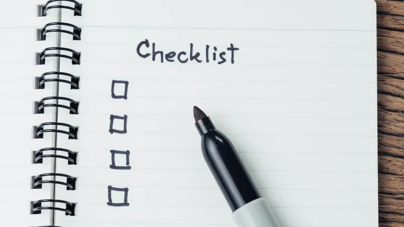 Pet sitter checklist written in a spiral notebook with a marker
